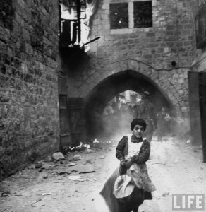Rachel Levy, 7 ans, s'enfuit d'une rue de Jérusalem en plein pillage par les Arabes, après la capitulation du quartier juif, 28 mai 1948
